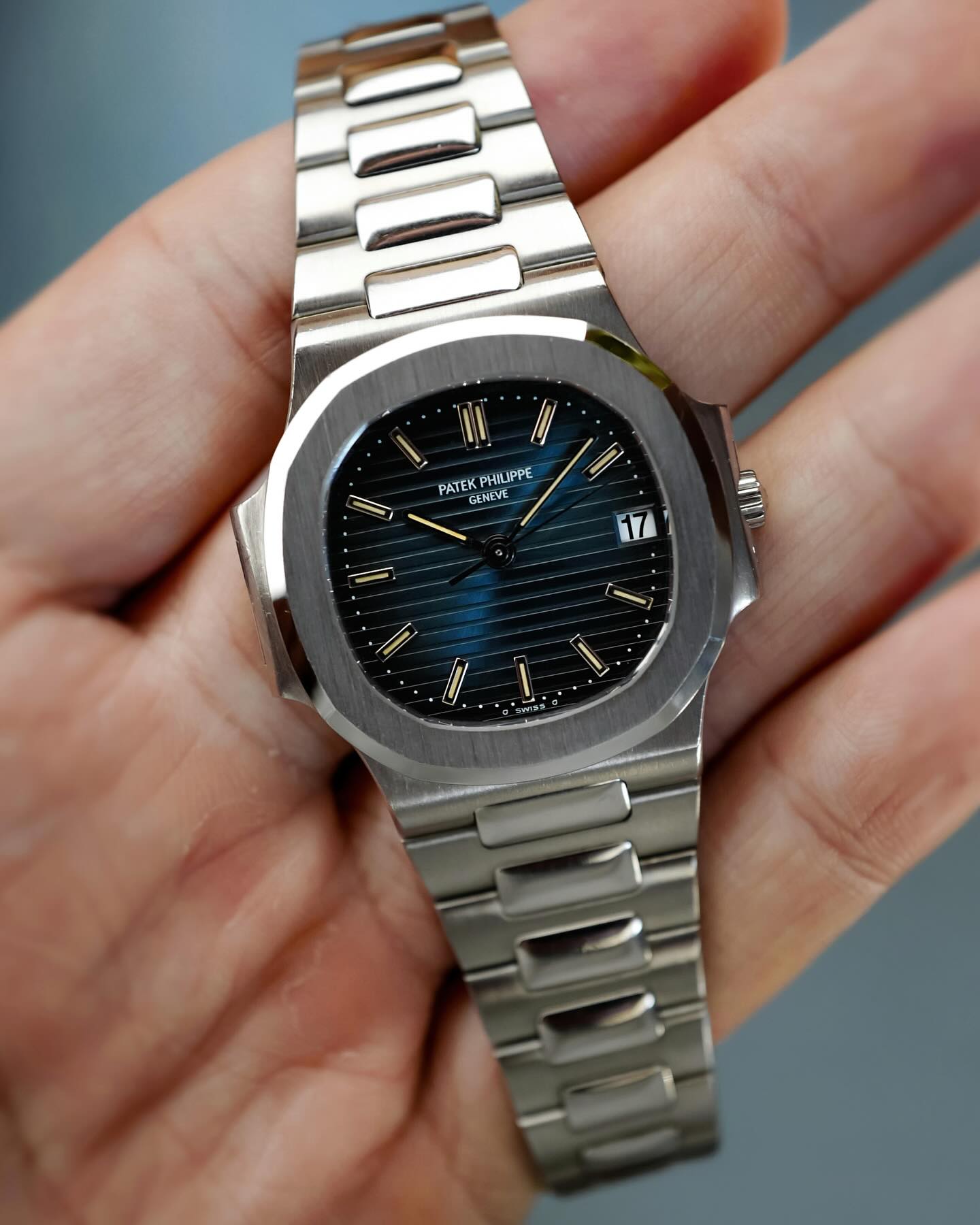 Patek Philippe Nautilus in steel with blue dial held in hand.